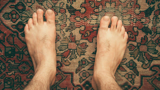 Top-view of bare feet on patterned carpet illustrating natural foot changes over time