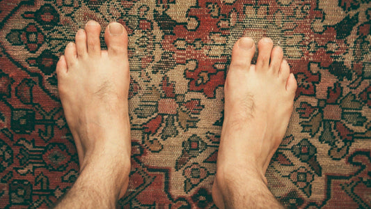 Top-view of bare feet on patterned carpet illustrating natural foot changes over time